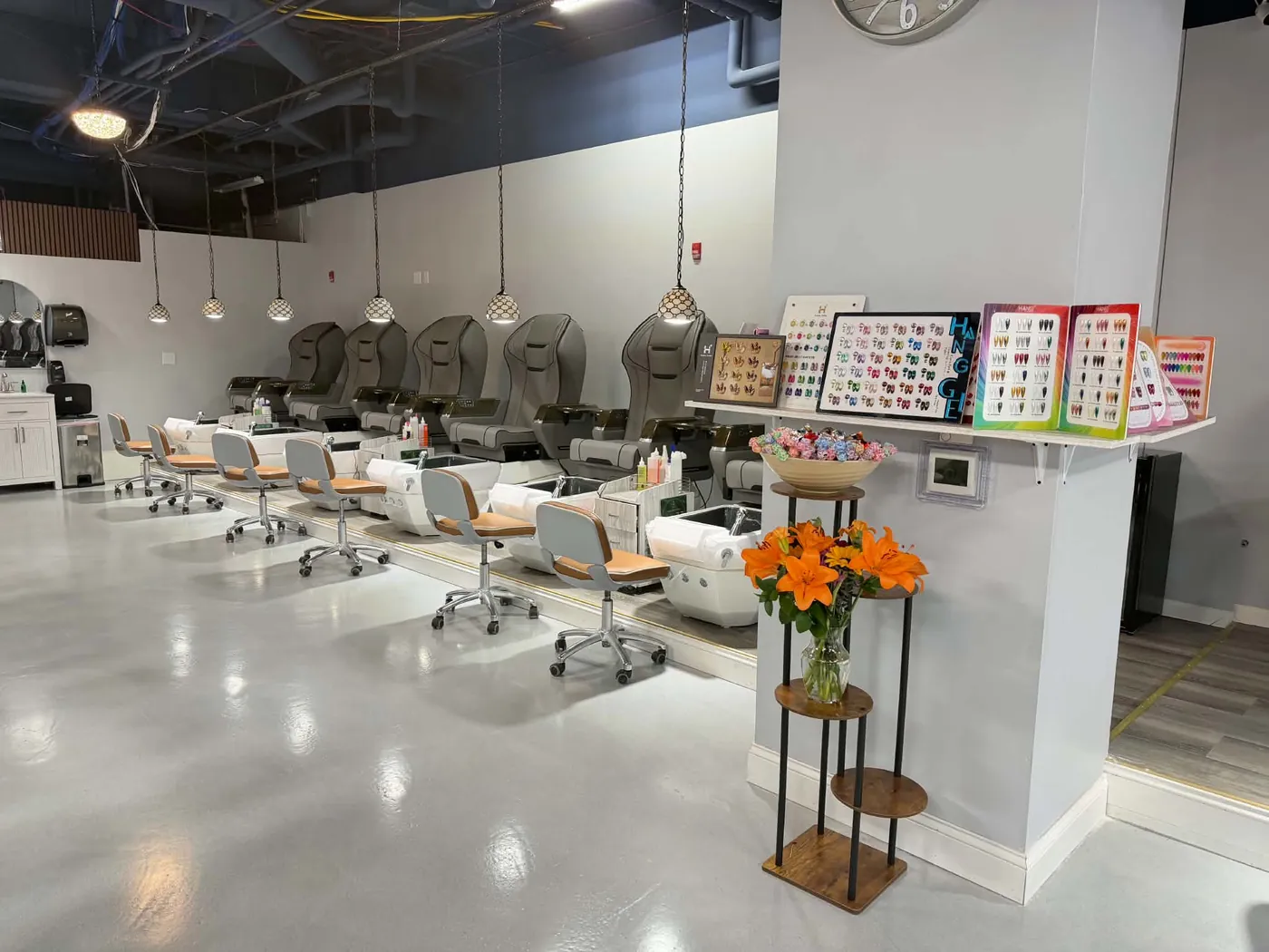 Inside the salon: a row of pedicure chairs, gel color charts and fresh lilies