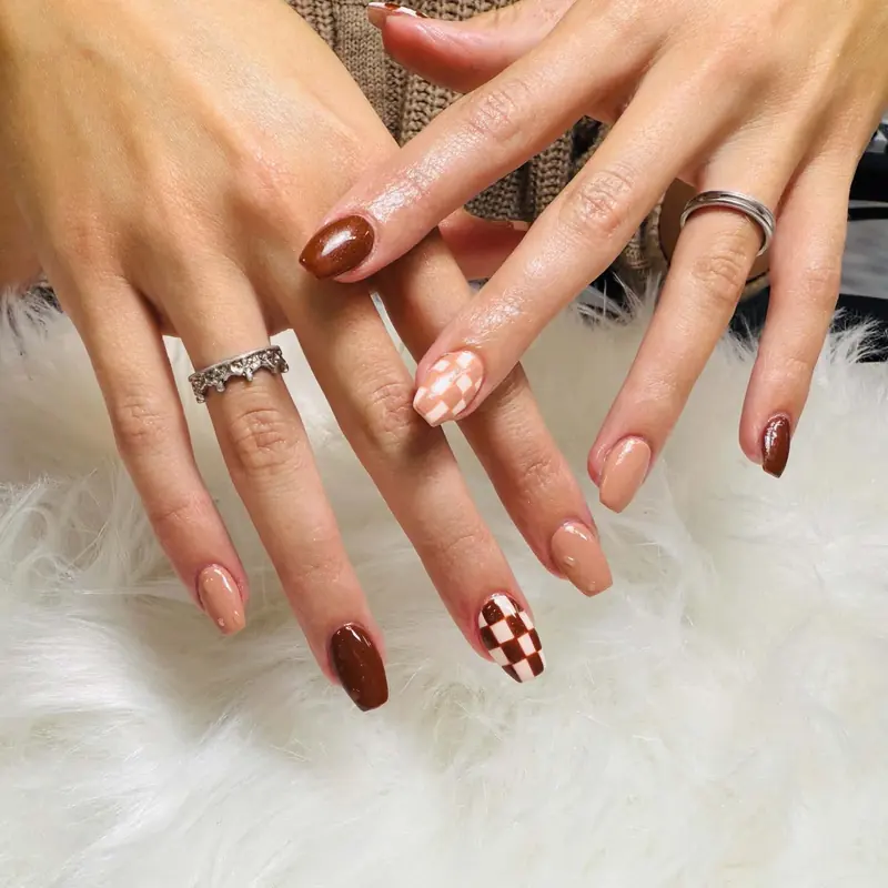 Brown nails with a checkerboard accent nail