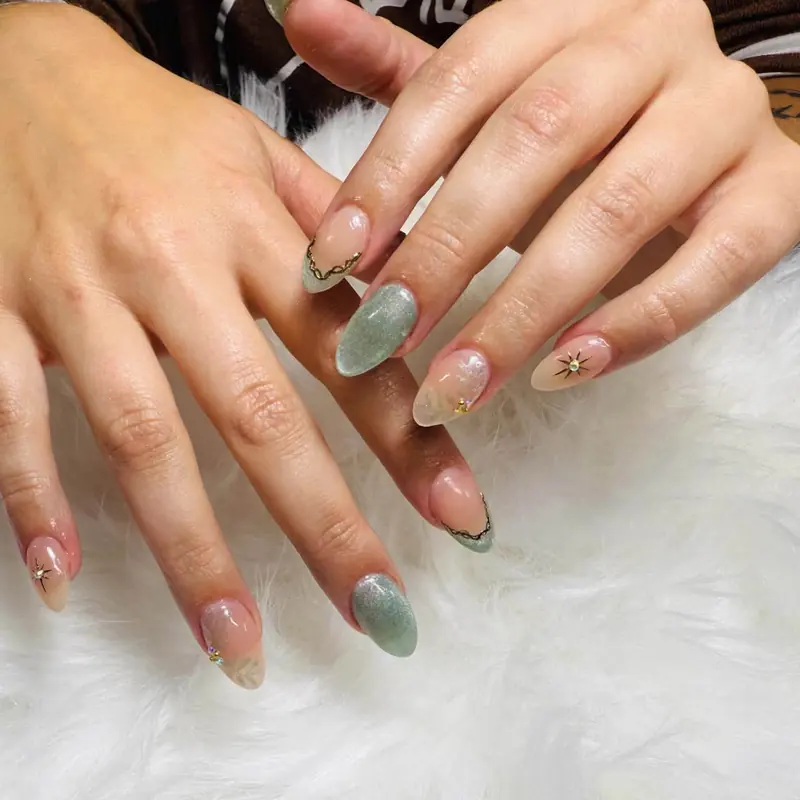Sage green almond nails with gold star accents
